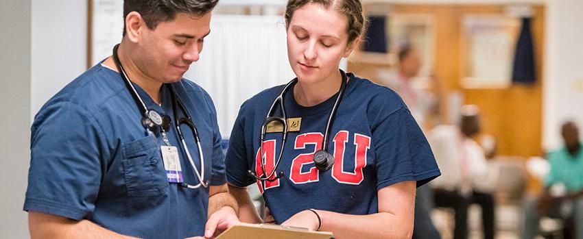 Female and male looking at clipboard with stethoscopes around their necks.